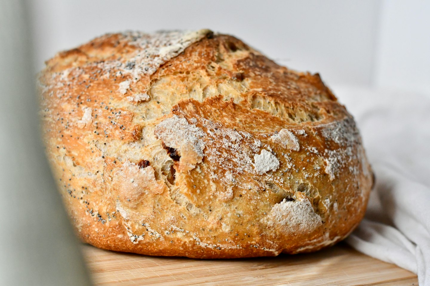 Una pagnotta di pane casereccio con semi di papavero su un tagliere.